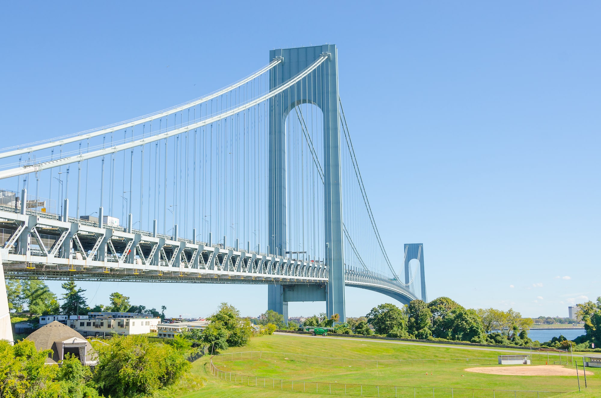 Beautiful Verrazano Narrows Bridge in New York painted a light blue color with homes and green grass below.
